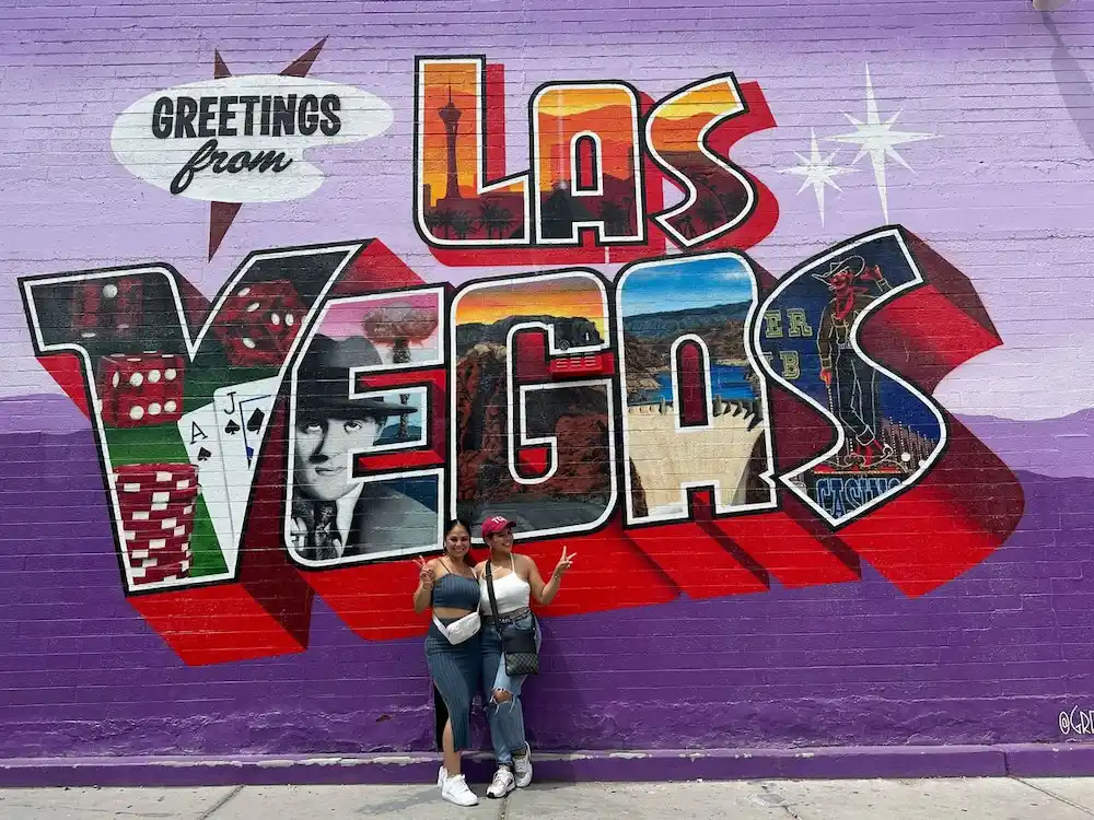 Guests posing in front of the Greetings from Las Vegas mural in the Arts District